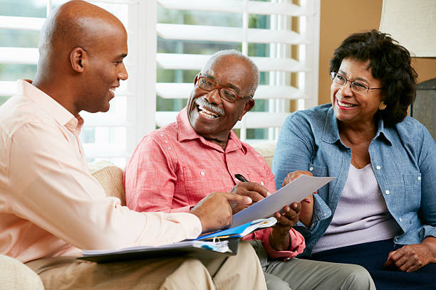 Financial Advisor Talking To Senior Couple At Home Smiling Financial Advisor Talking To Senior Couple At Home Smiling